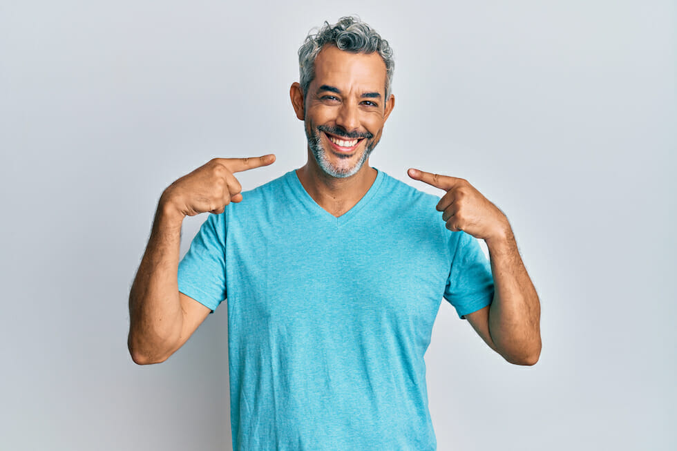 man with blue shirt point at his smile